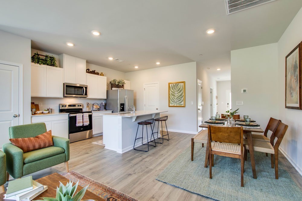 a living room with furniture a dining table kitchen view and a wooden floor