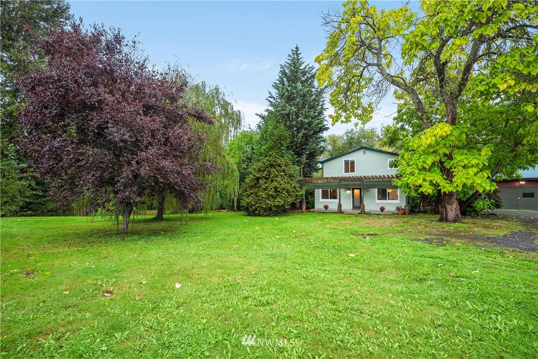 a view of a big house with a big yard and large trees