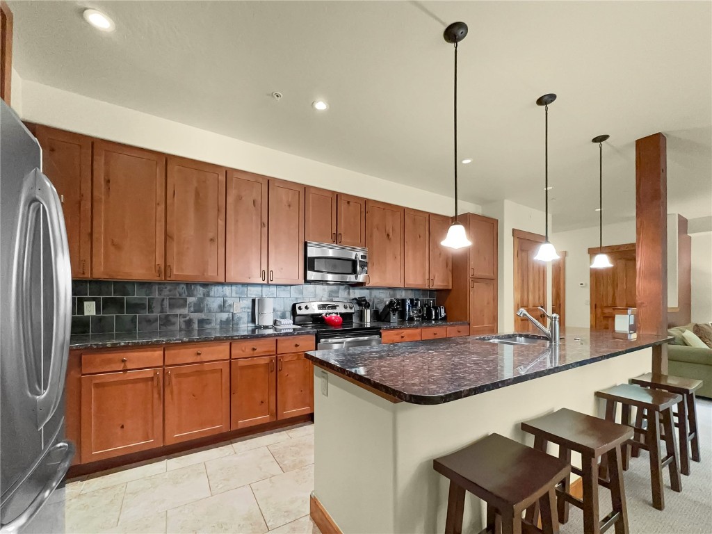 a kitchen with stainless steel appliances granite countertop a sink a stove and a wooden floors