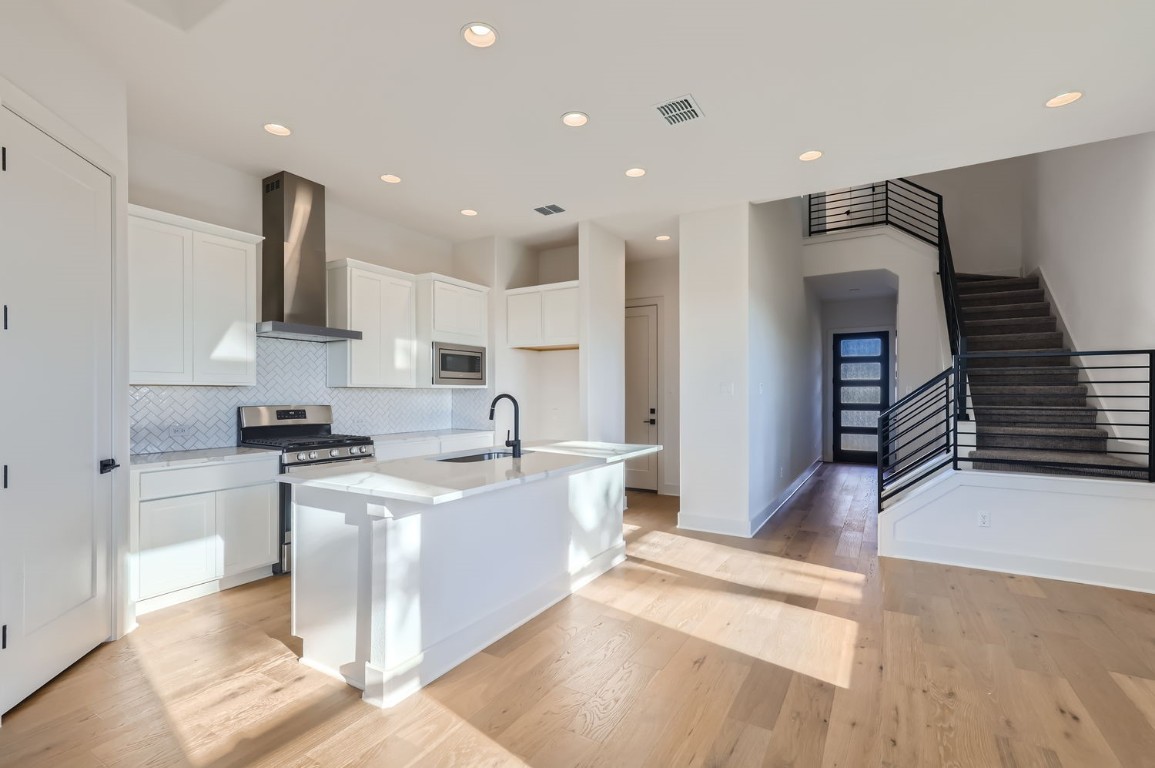 a kitchen with stainless steel appliances granite countertop a sink and a stove