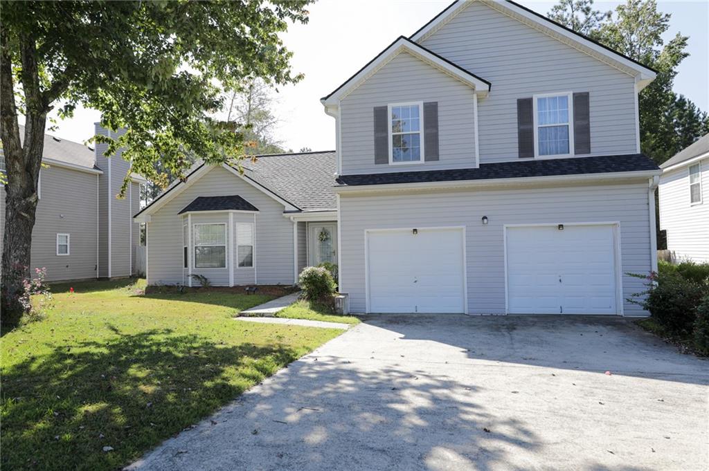 a front view of house with yard and trees in the background