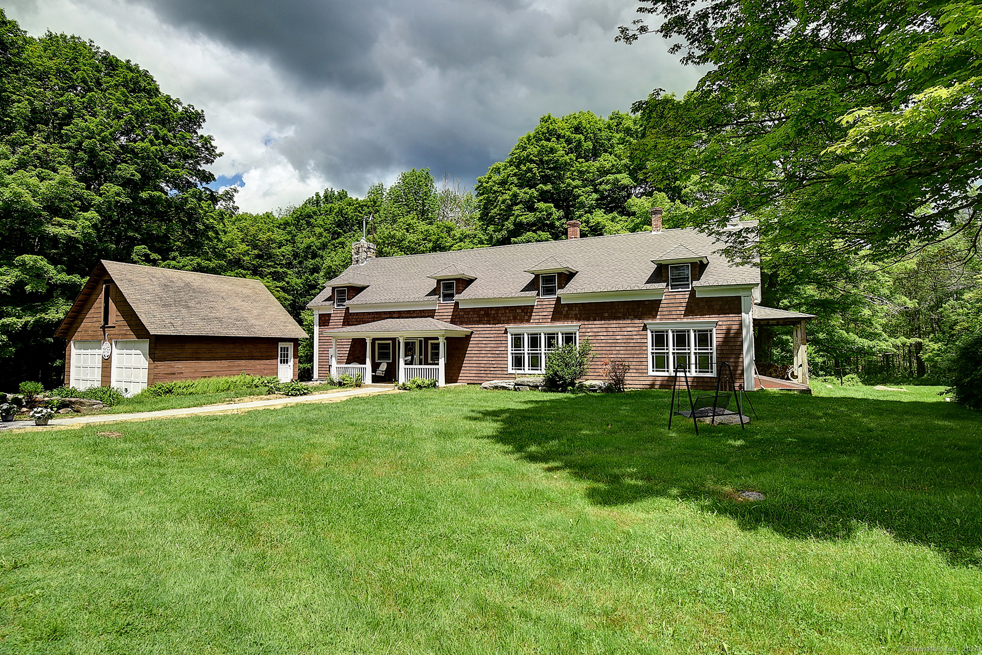 a view of a house with a big yard potted plants and large tree