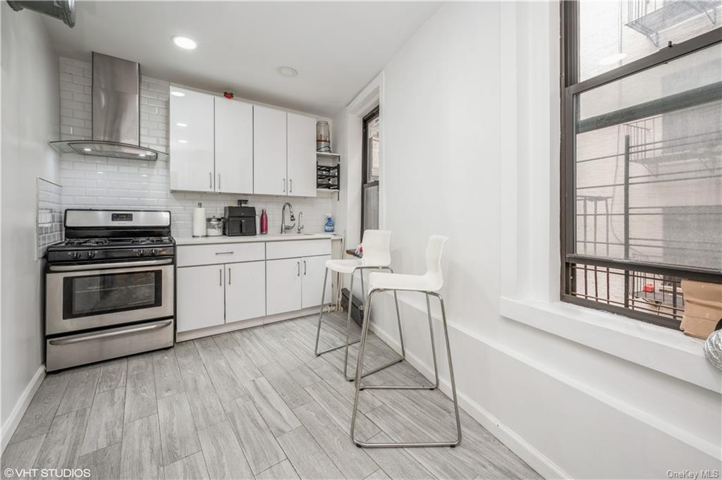 a kitchen with a stove a sink and white cabinets with wooden floor