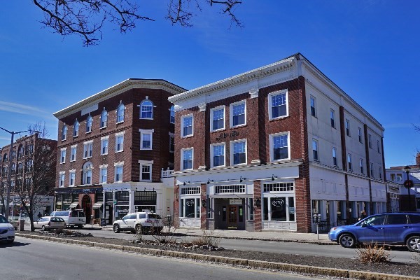 a front view of a building with lot of cars and trees