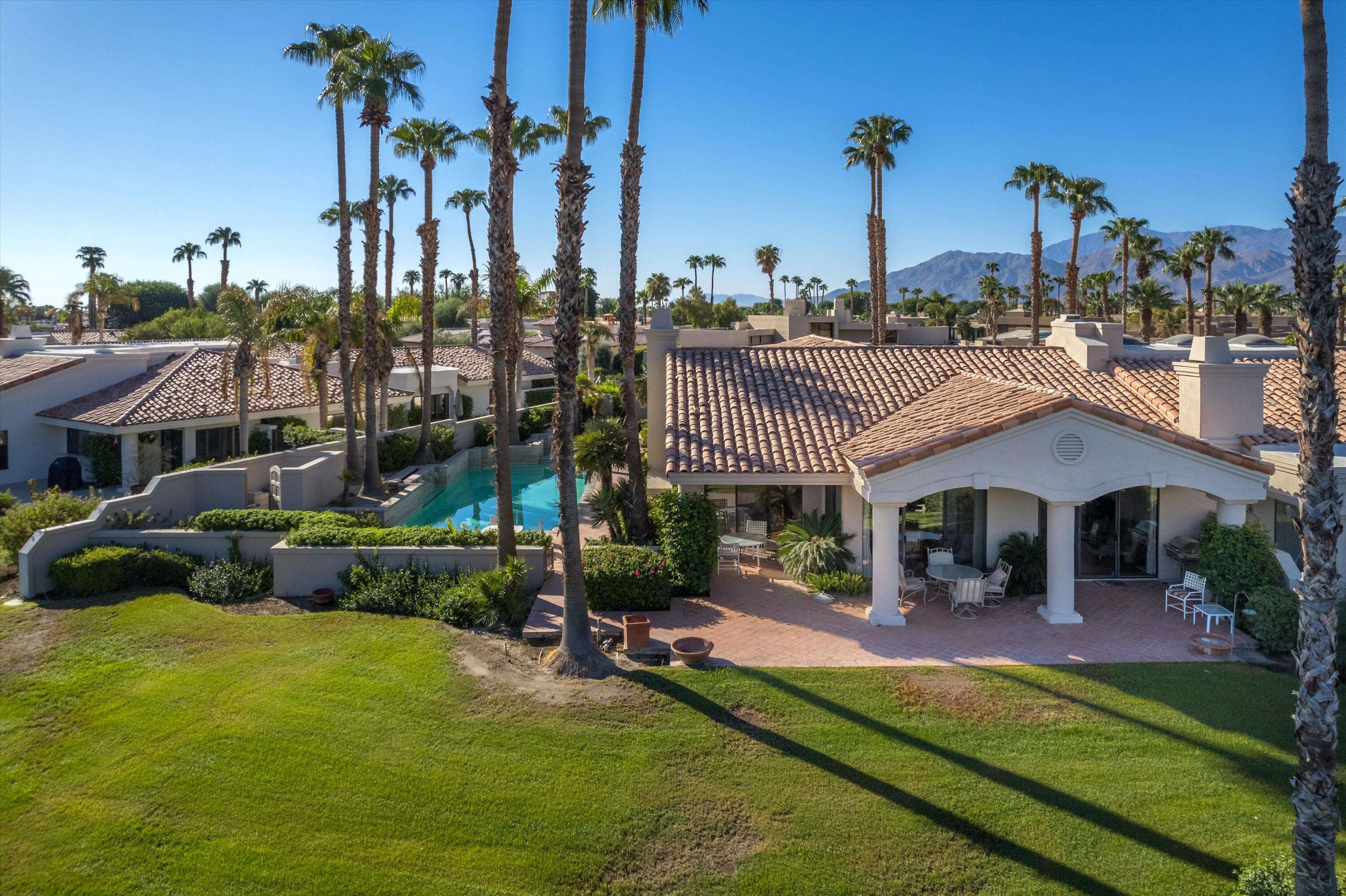 a view of a house with a swimming pool lawn chairs and a fire pit