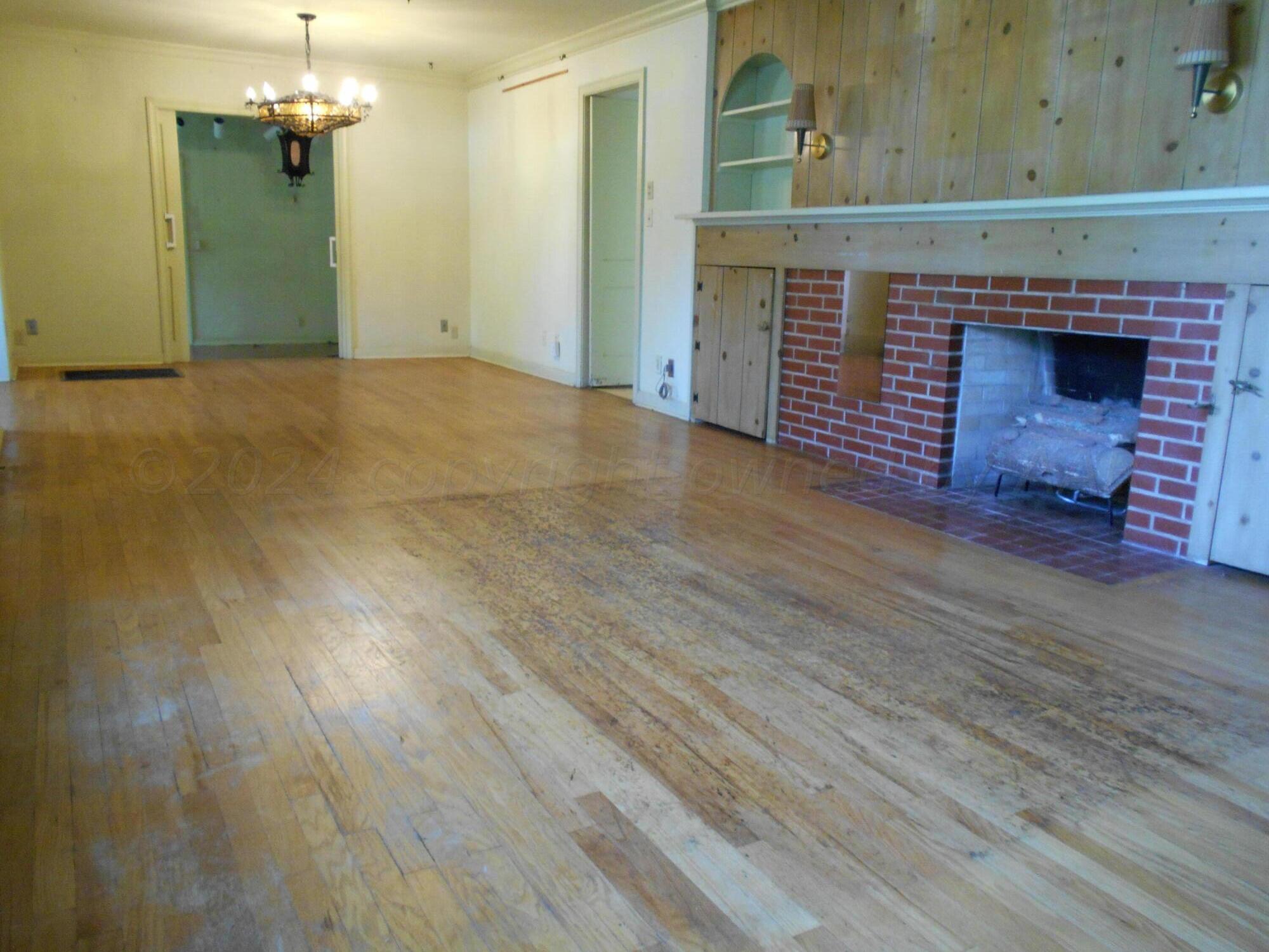 an empty room with wooden floor fireplace and windows