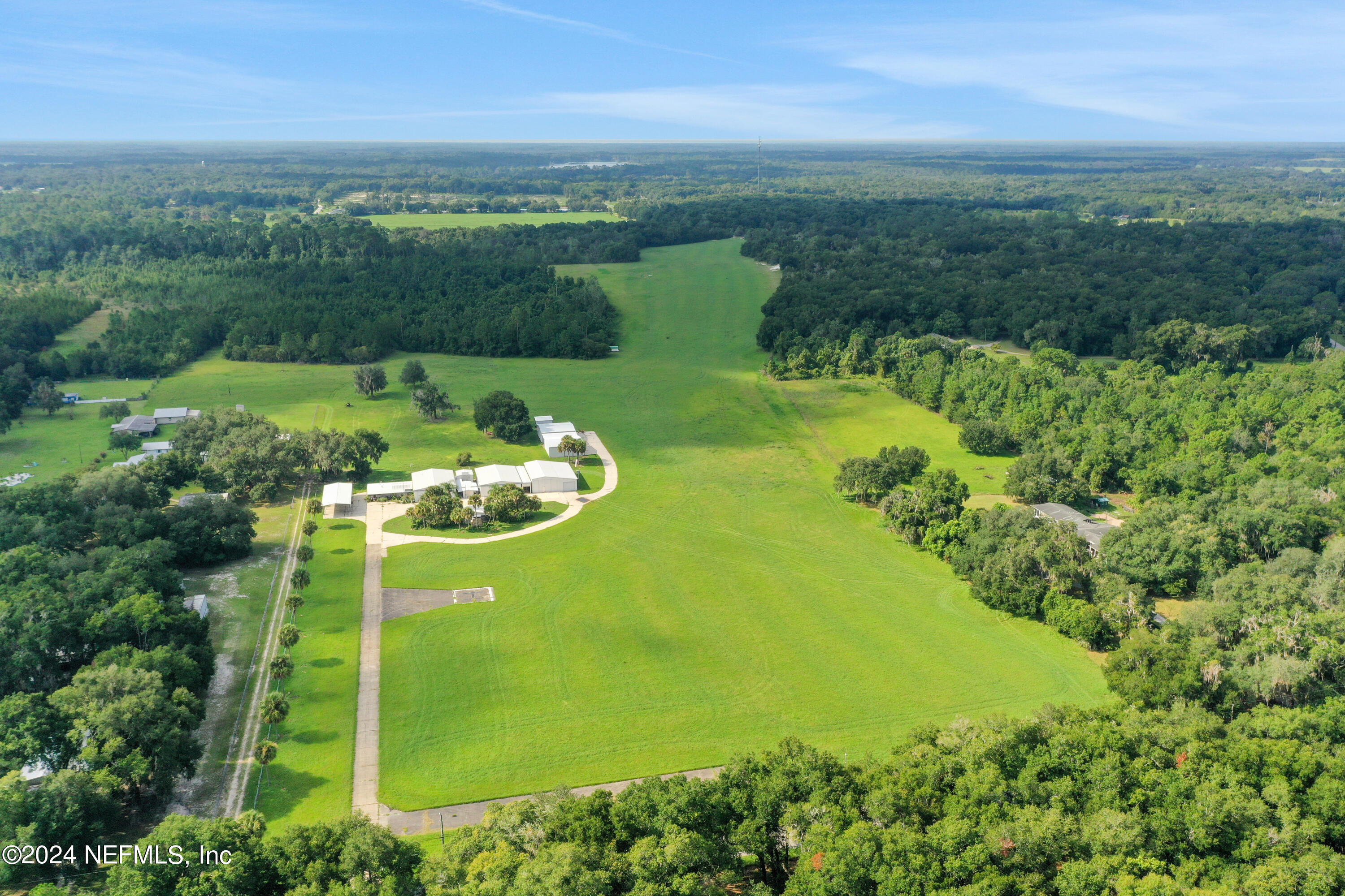 an aerial view of a residential houses with outdoor space and trees all around