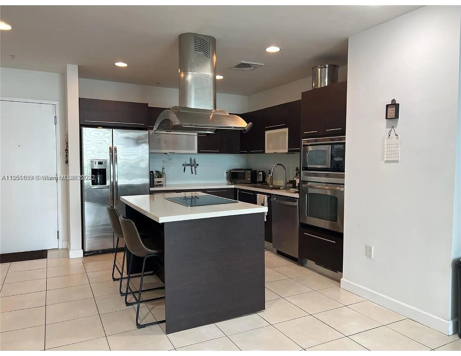 a kitchen with a sink a refrigerator and chairs