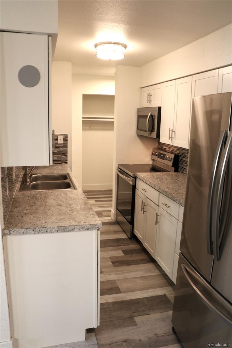 a kitchen with stainless steel appliances granite countertop a refrigerator a stove and a sink