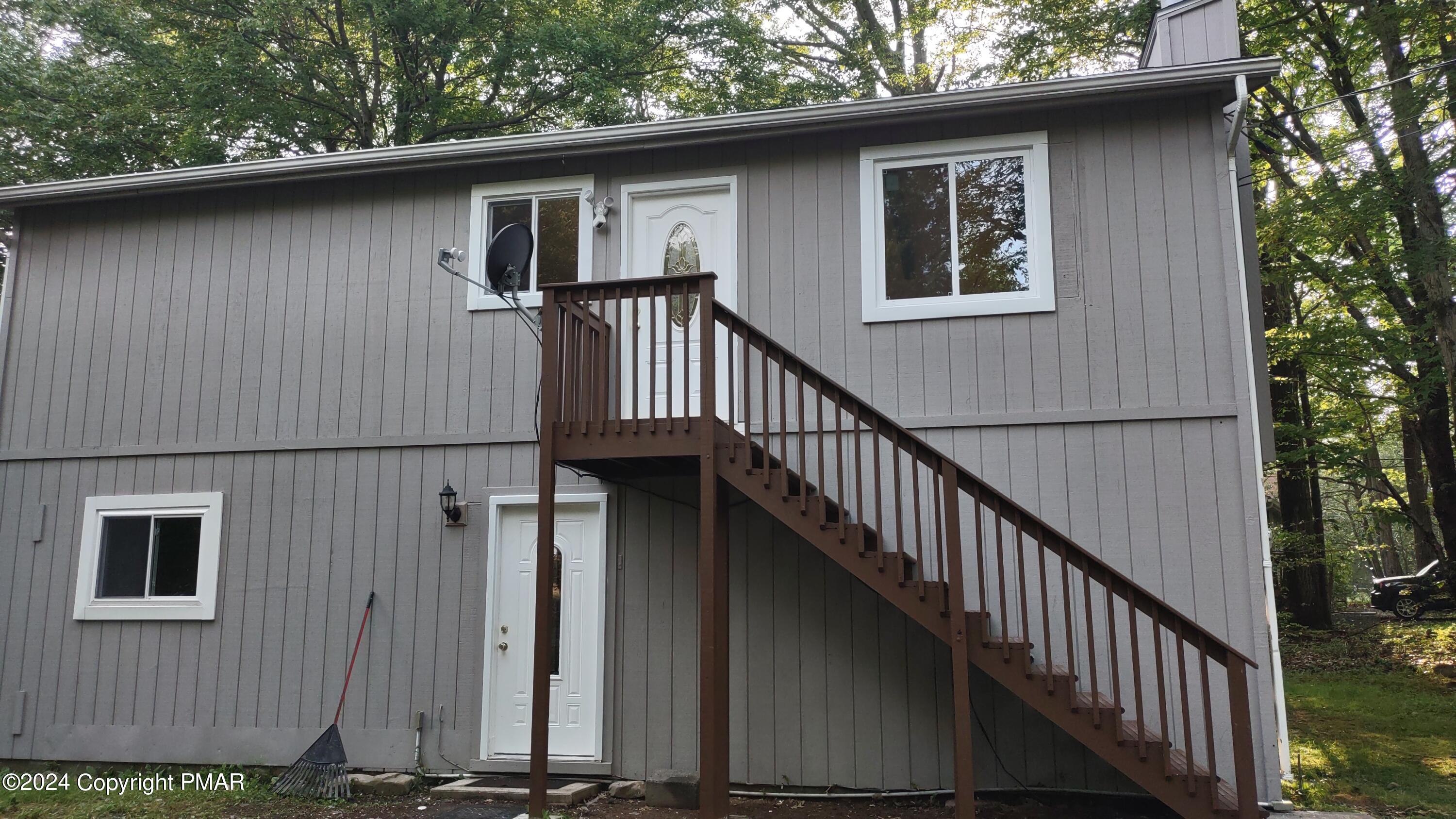 a view of backyard of house with wooden deck and furniture