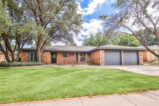 a front view of a house with a yard and trees