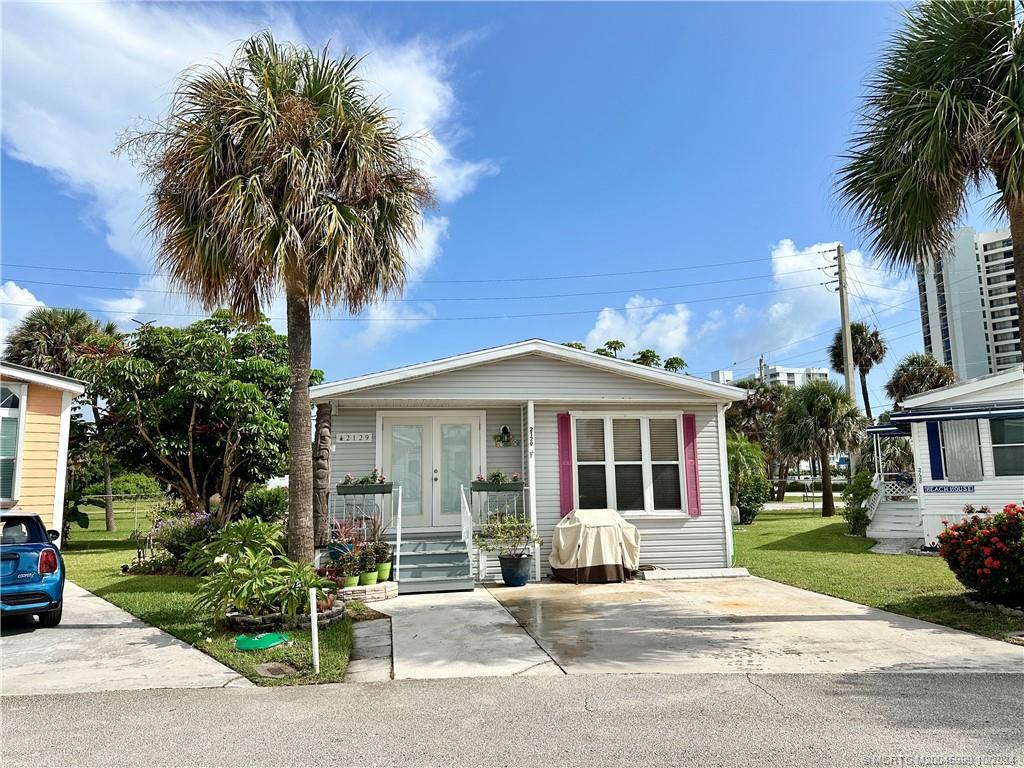 a front view of a house with a garden and palm trees