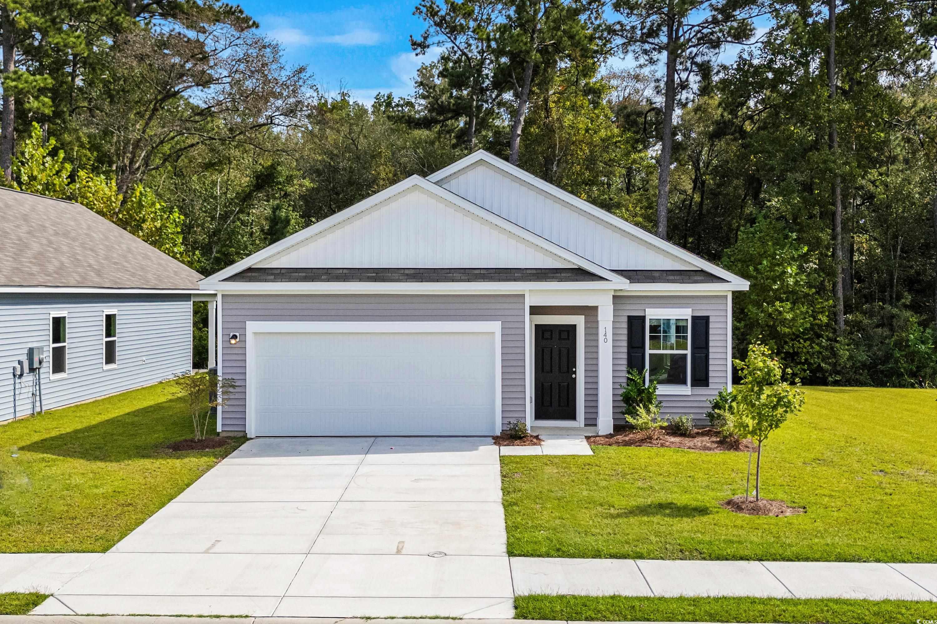 View of front of home with a front yard and a gara