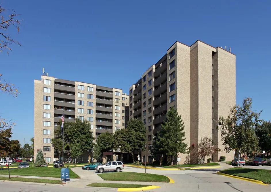 a front view of multi story residential apartment building with yard and trees