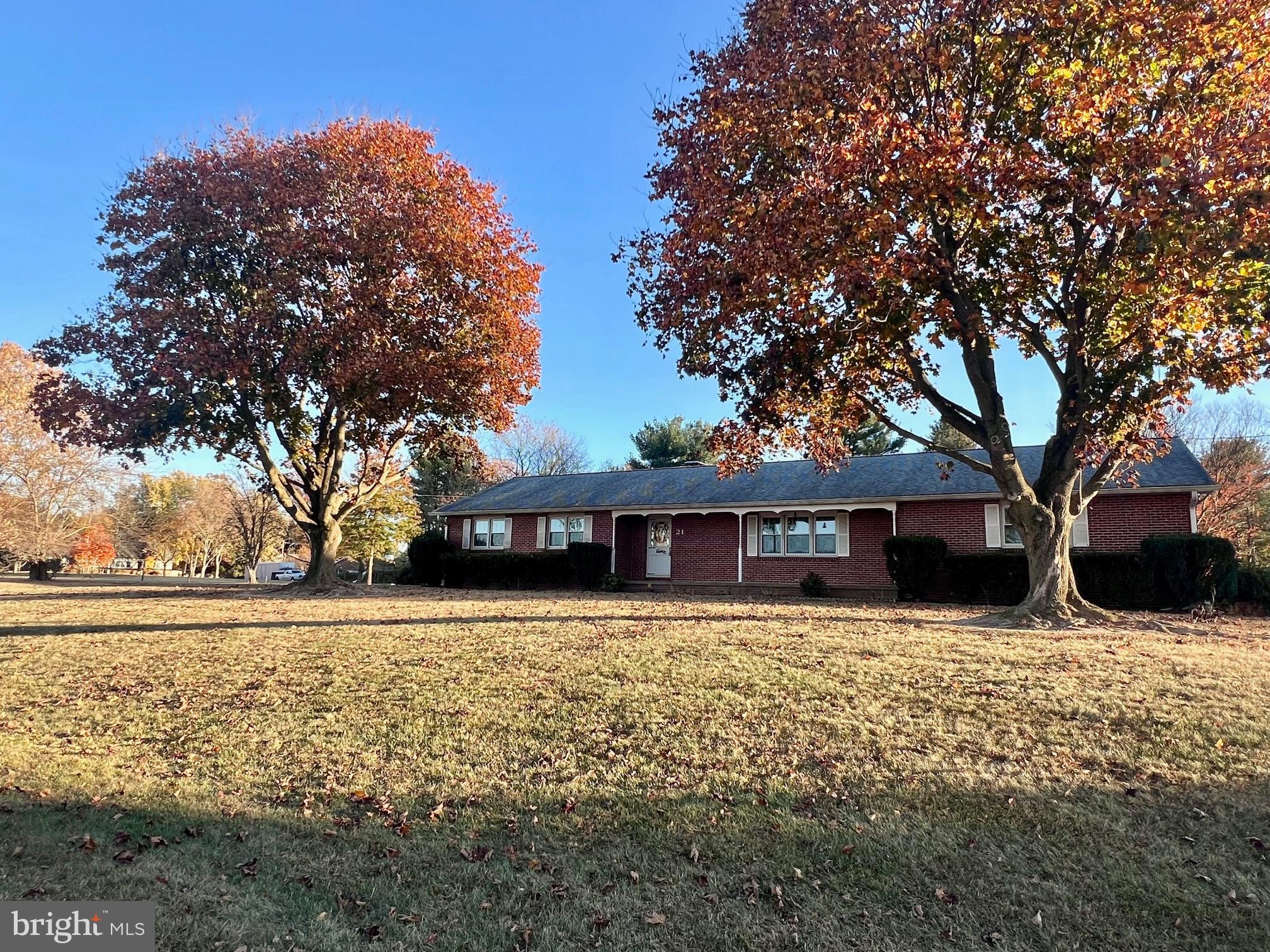 a front view of a house with a yard covered with trees