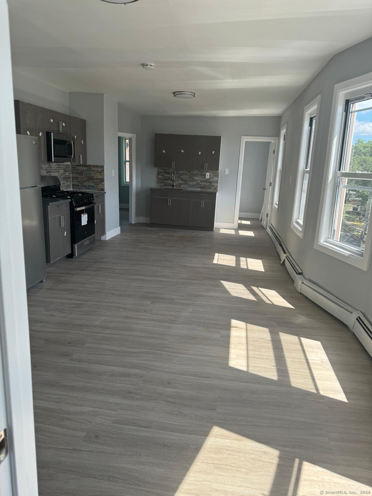 a view of an empty room and a kitchen