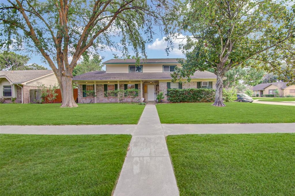 a view of house with a big yard potted plants and large trees