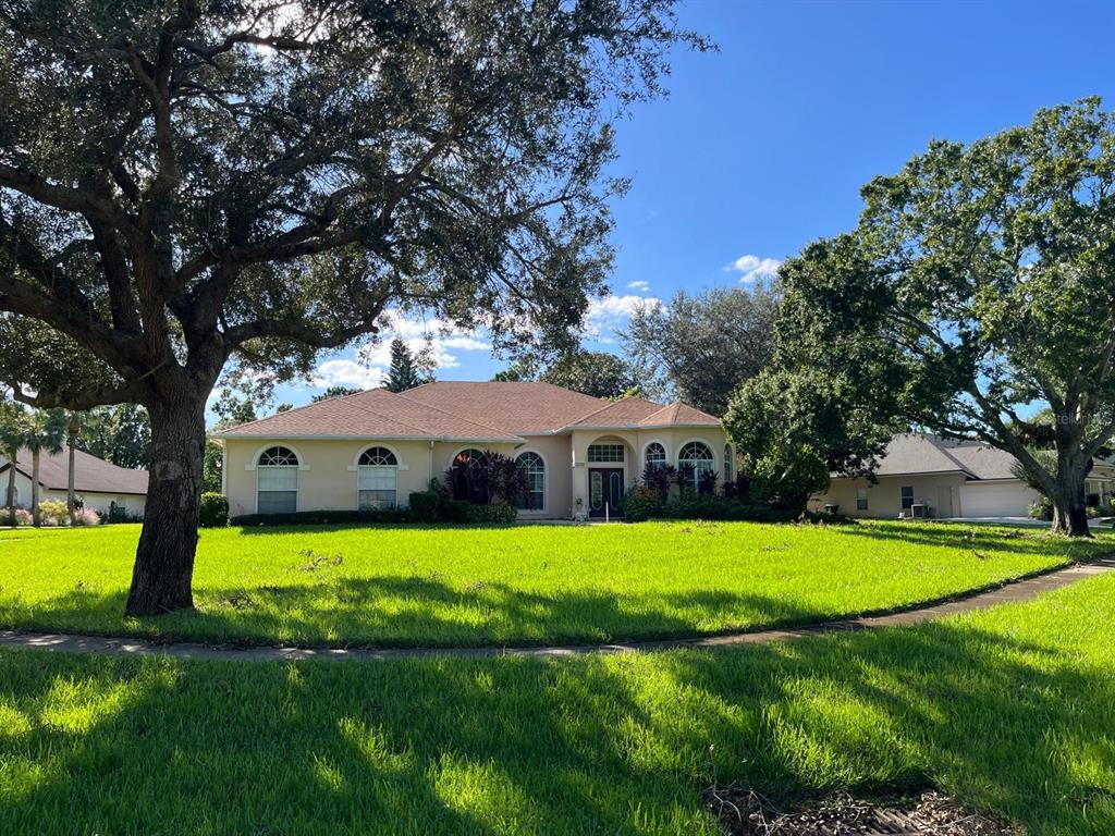 a view of a house with a big yard and palm trees