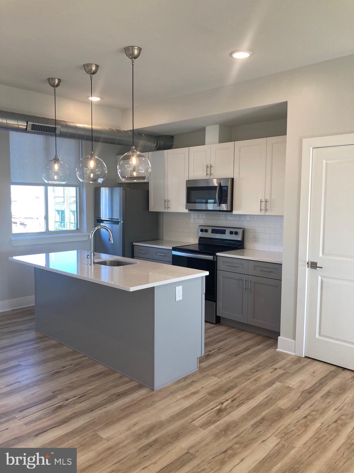 a kitchen with kitchen island a sink a counter top space stainless steel appliances and cabinets