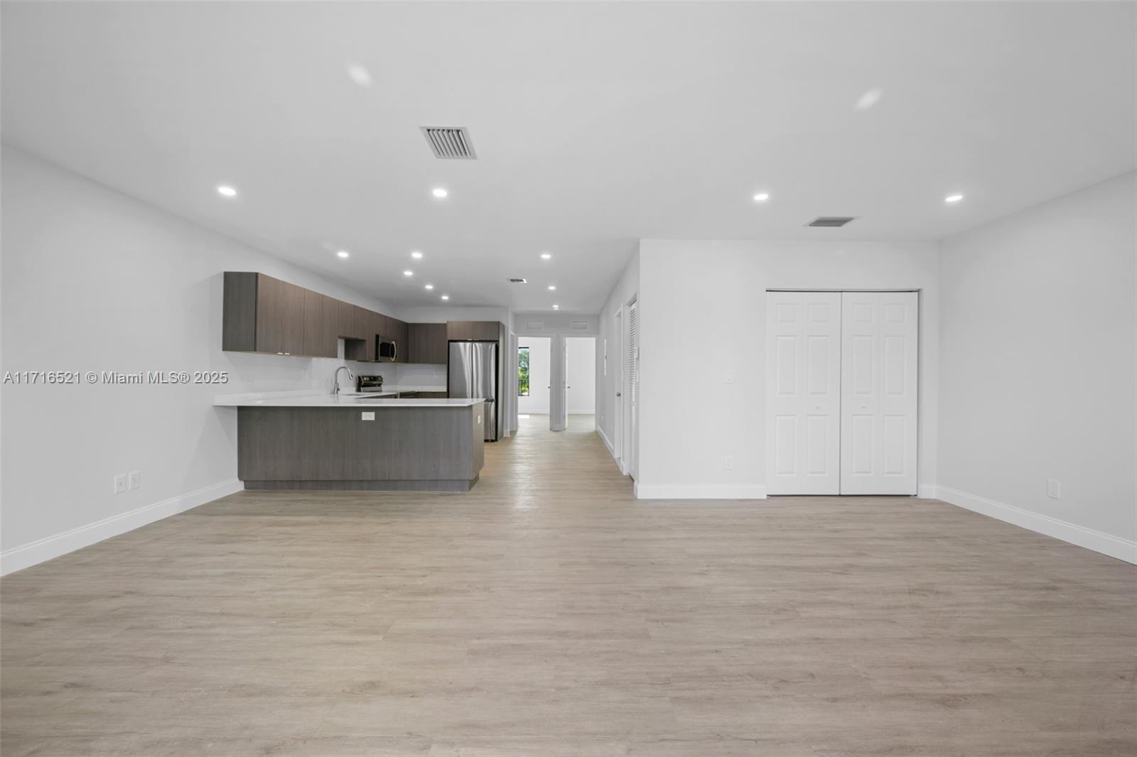 a view of kitchen with kitchen island a sink wooden floor and a refrigerator