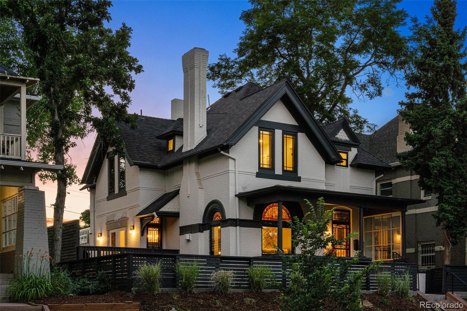 a front view of a house with large trees