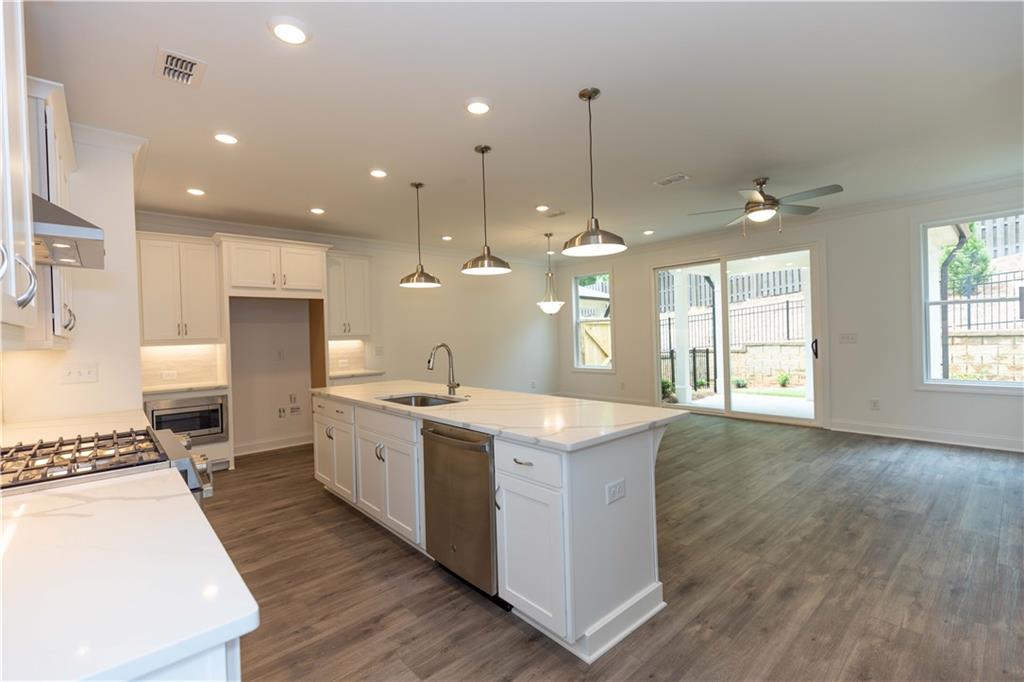 a large kitchen with kitchen island a stove a sink a center island and wooden floor
