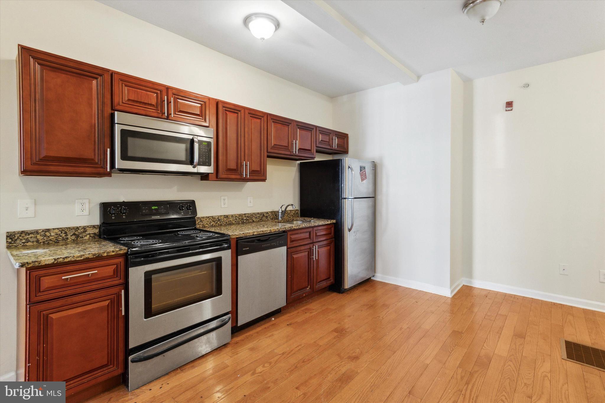 a kitchen with granite countertop wooden cabinets stainless steel appliances and a counter space