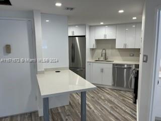 a kitchen with kitchen island white cabinets appliances and wooden floor