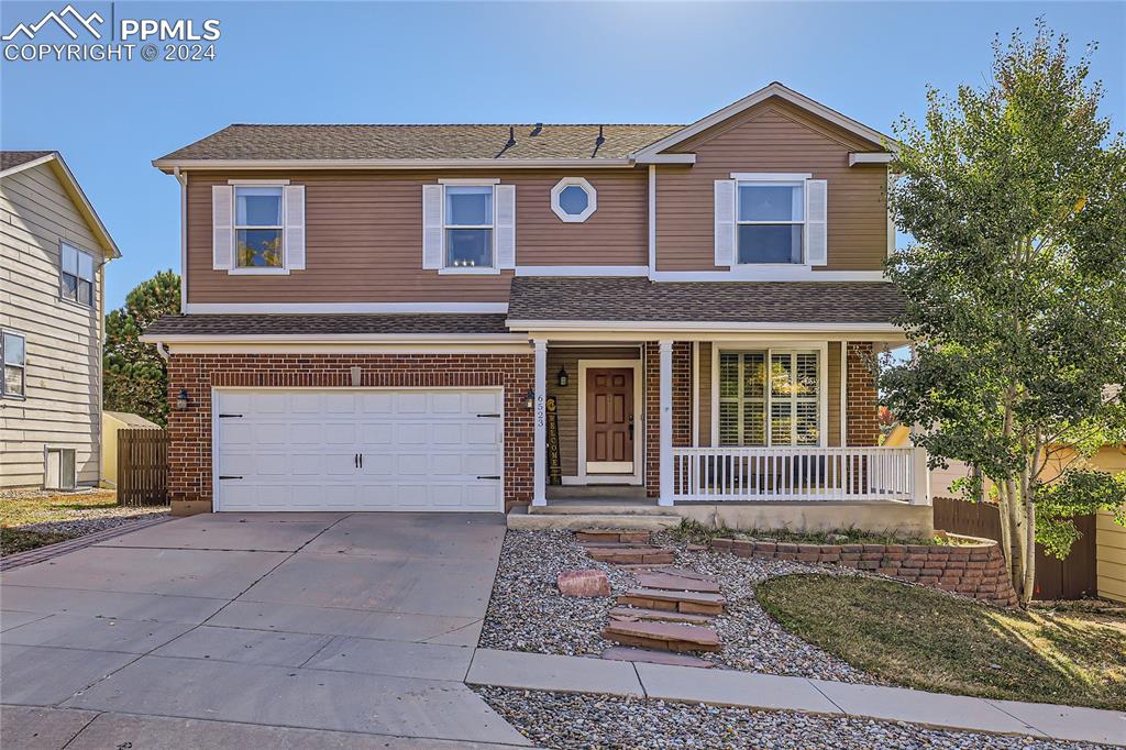 View of front of home with a porch and a garage