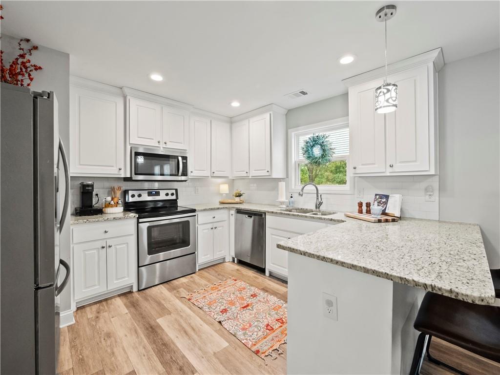 a kitchen with granite countertop a sink stainless steel appliances and white cabinets