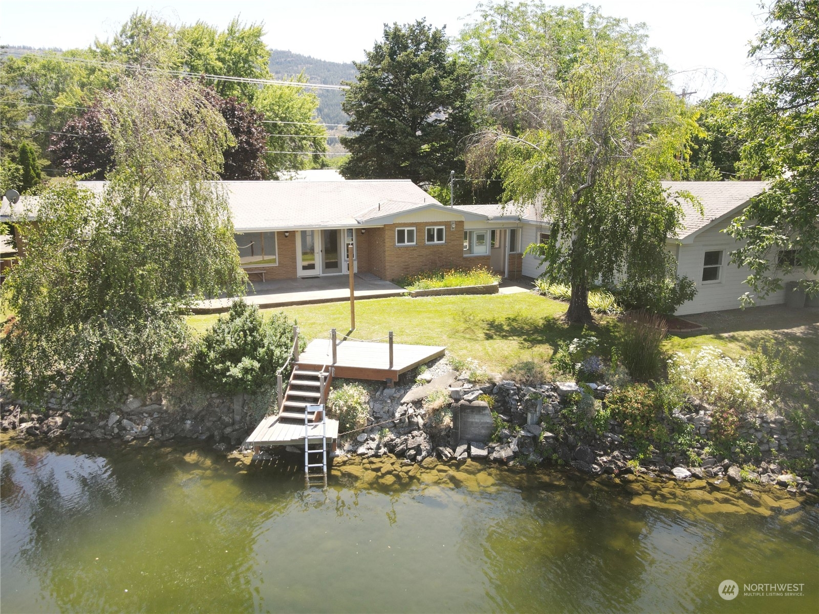 a view of a lake with a yard and a large tree