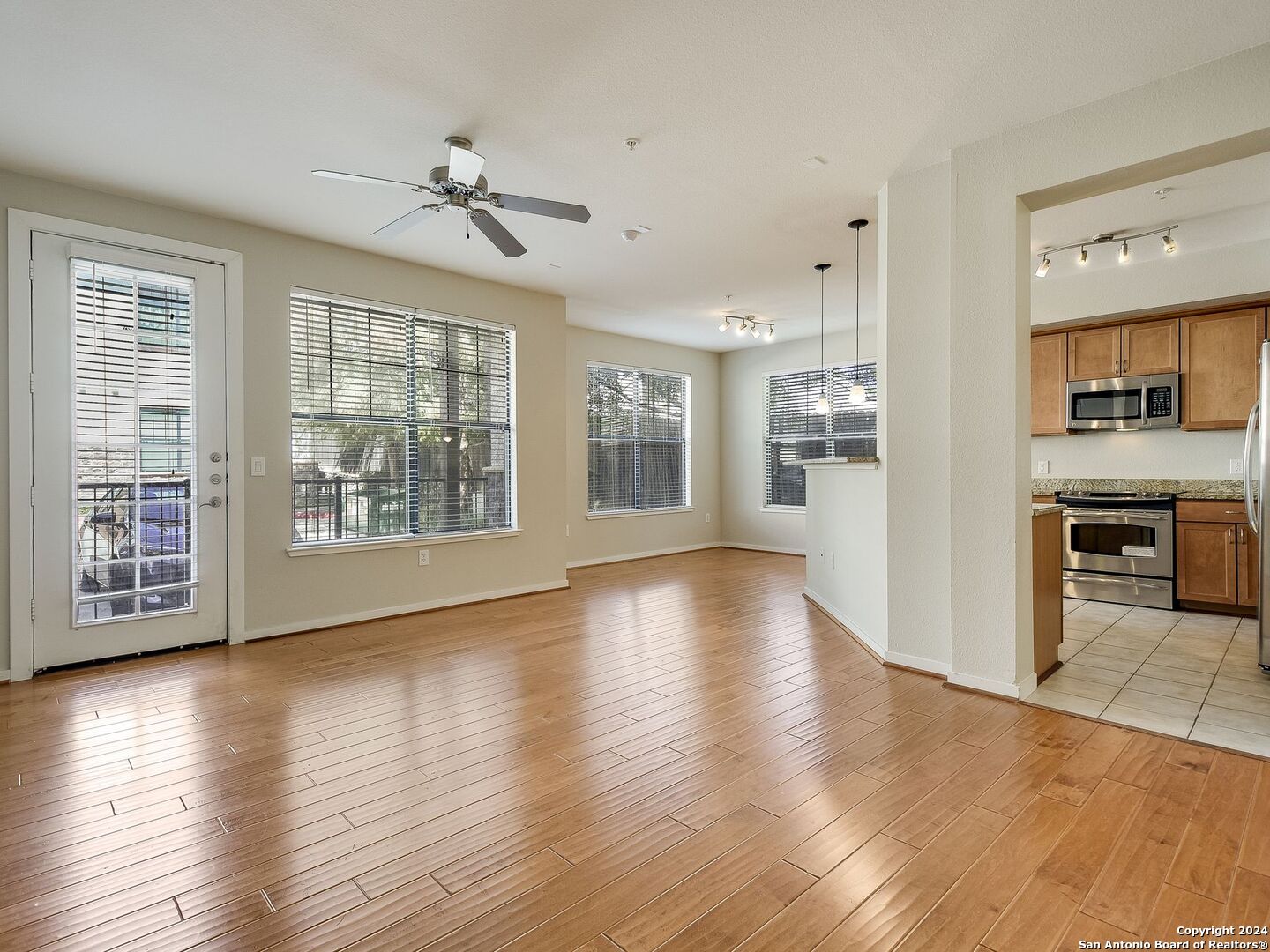 a view of an empty room with a kitchen and wooden floor