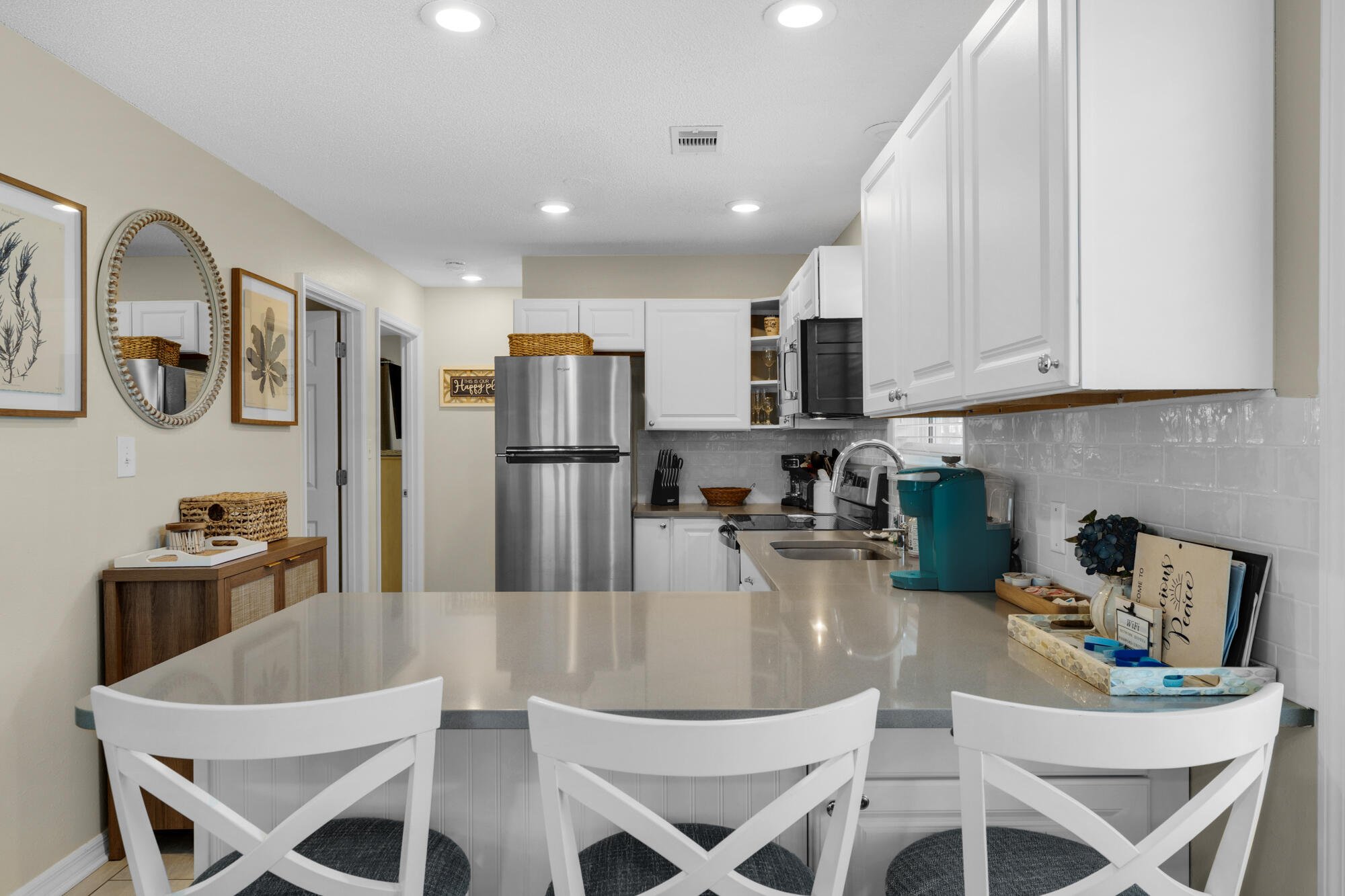 a kitchen with stainless steel appliances granite countertop a dining table chairs and refrigerator