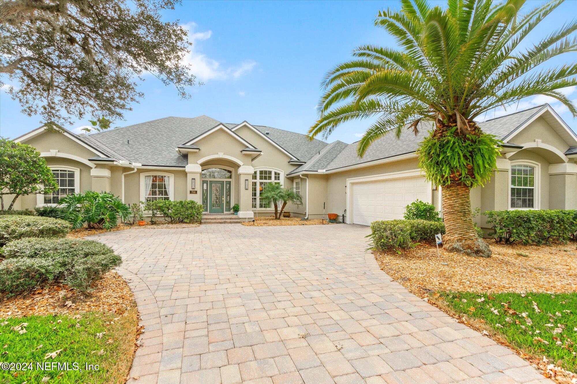 a front view of a house with a garden and trees