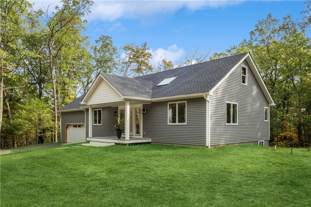 View of front of home with a porch, a garage, and a front yard