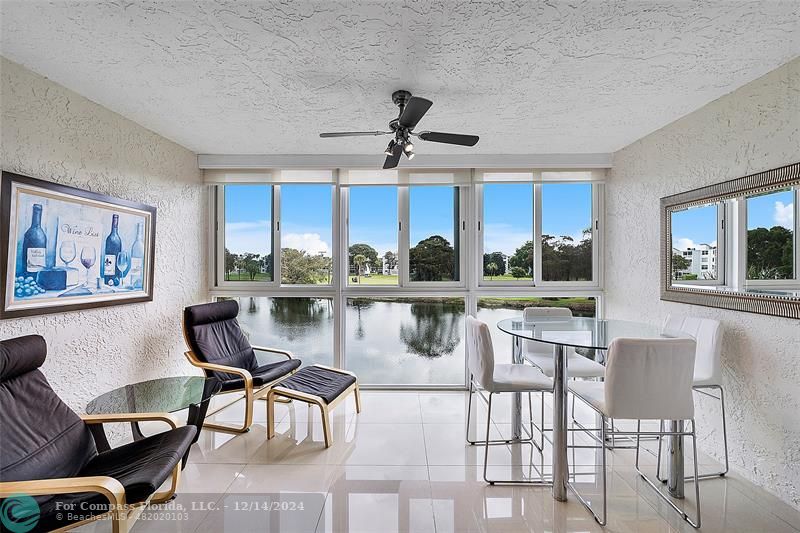 a dinning room with stainless steel appliances kitchen island granite countertop a dining table chairs and a two large window