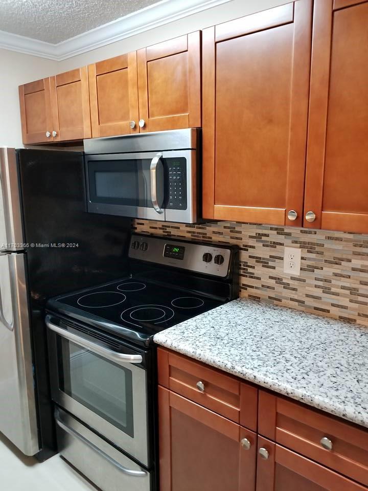 a kitchen with granite countertop wooden cabinets and a stove top oven