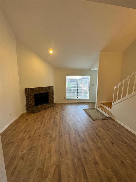 a view of empty room with wooden floor and fireplace