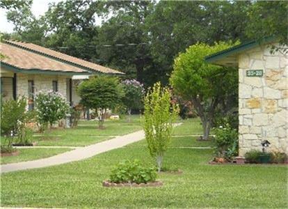 a view of a white house next to a yard with big trees