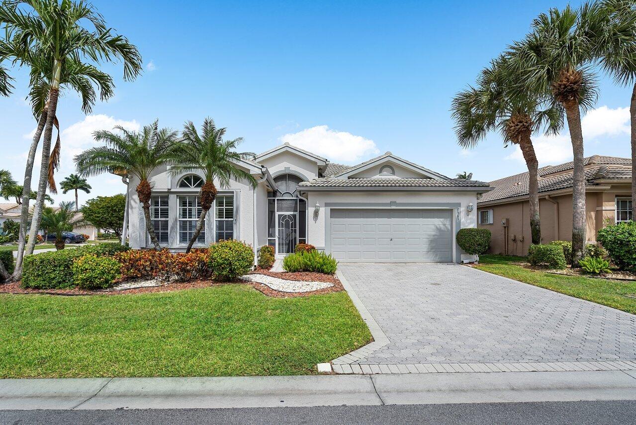 a front view of a house with a garden and palm trees