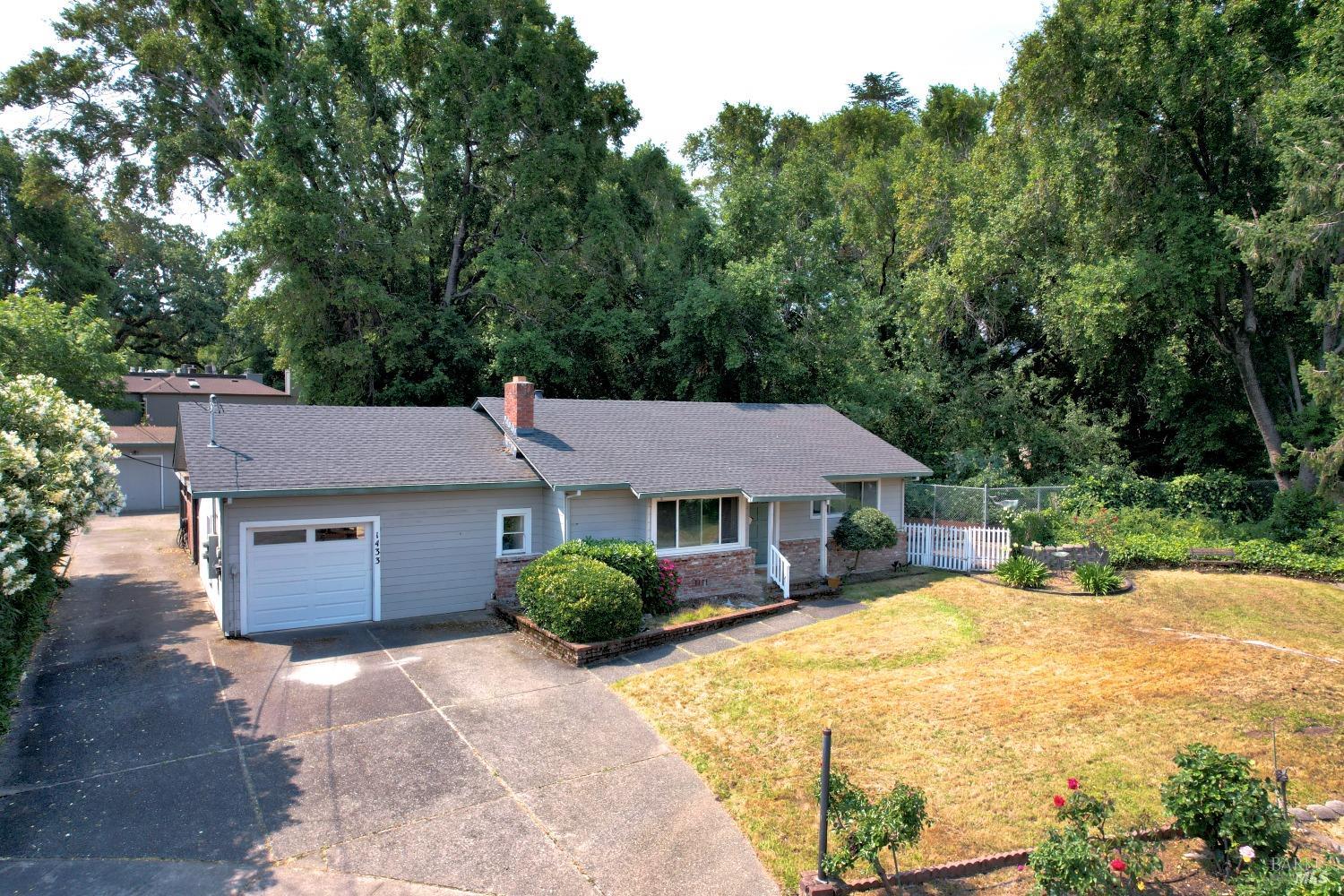 a front view of a house with a garden and trees