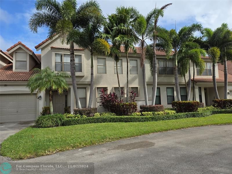 front view of a house with a yard and palm trees