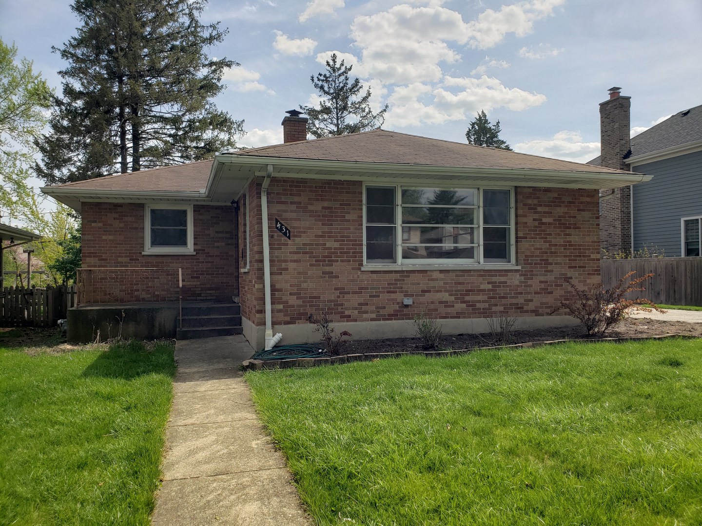 a view of a brick house with a small yard and a large tree