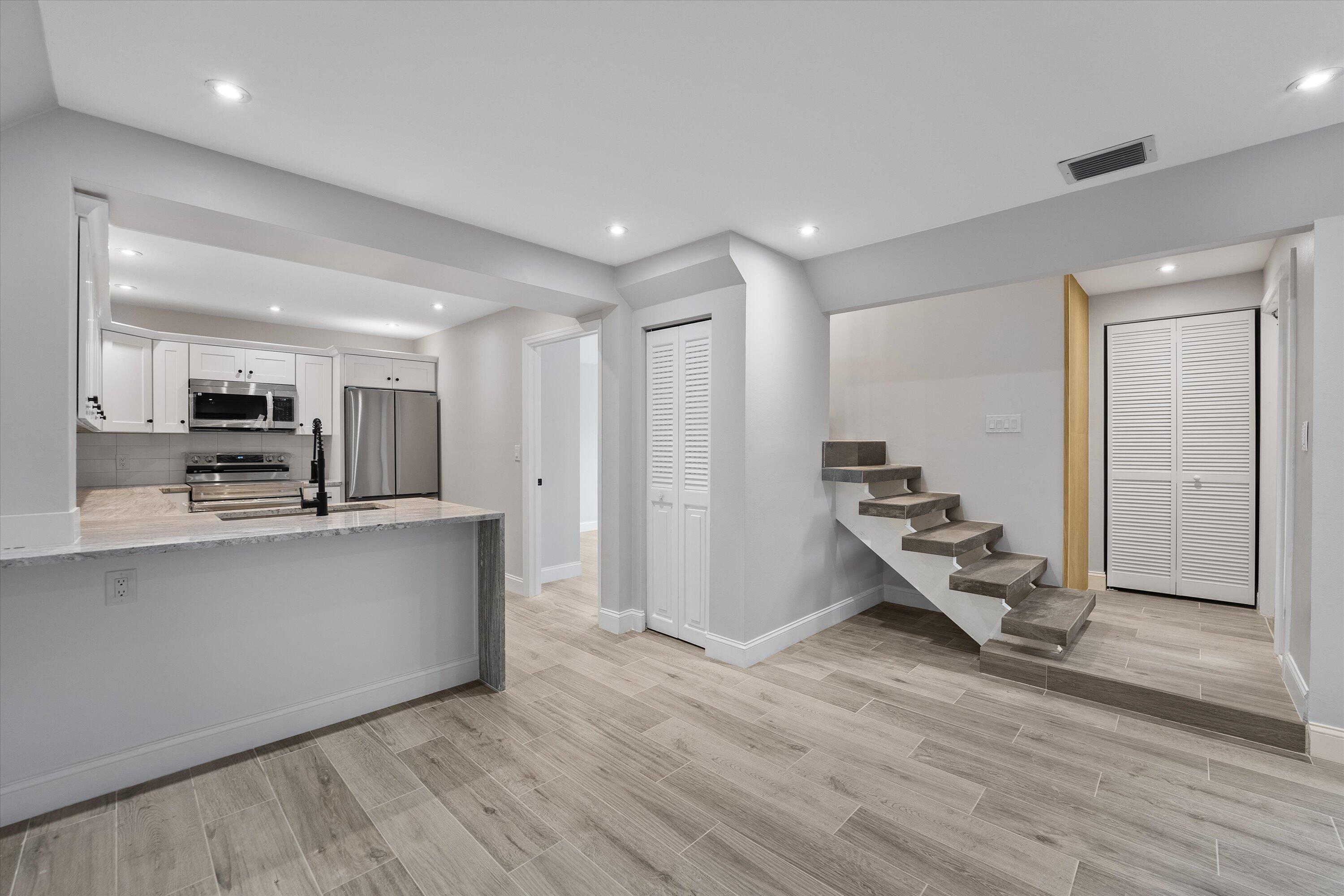 a living room with stainless steel appliances kitchen island granite countertop a stove and a refrigerator