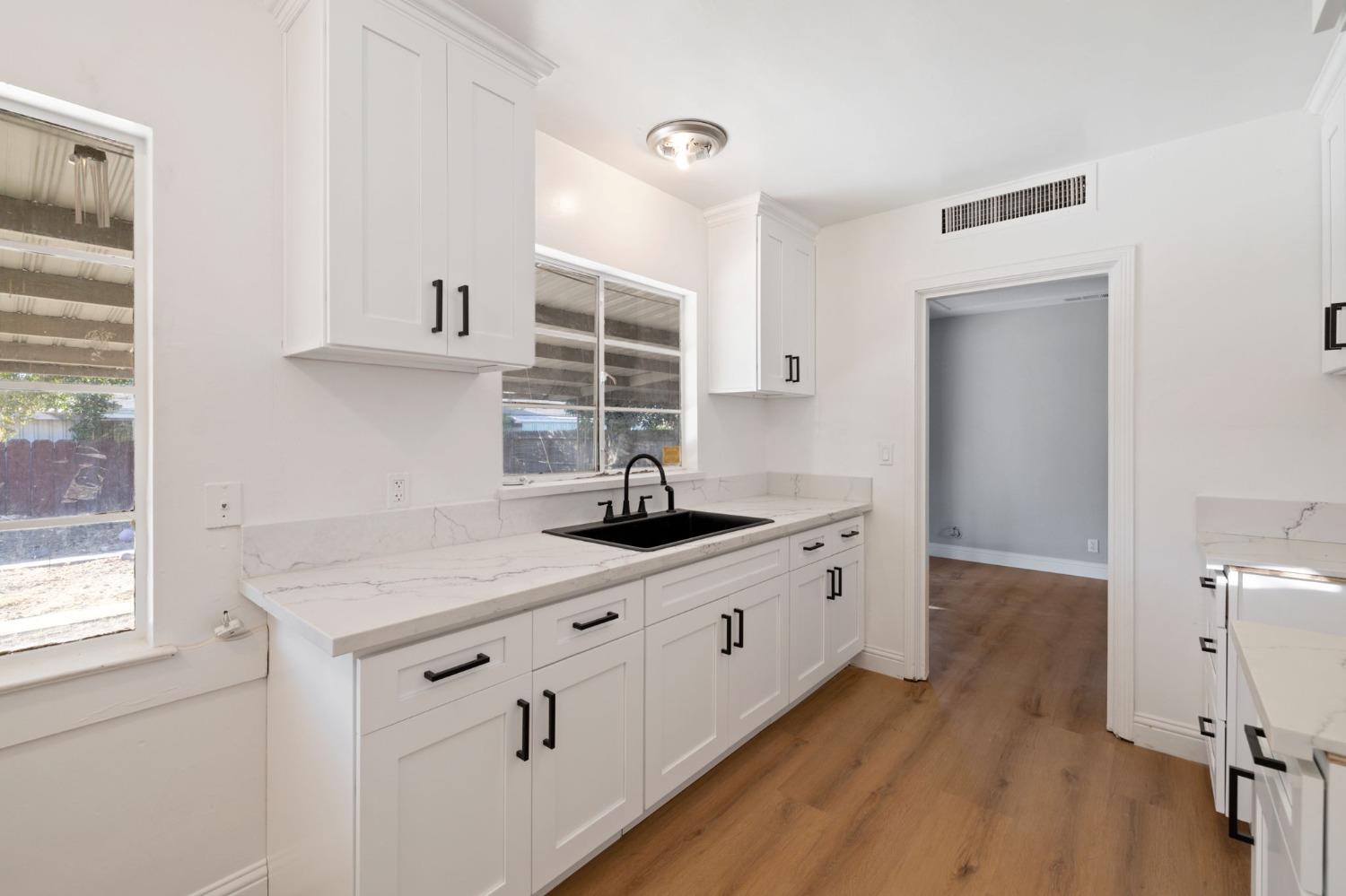 a kitchen with granite countertop a sink cabinets and wooden floor