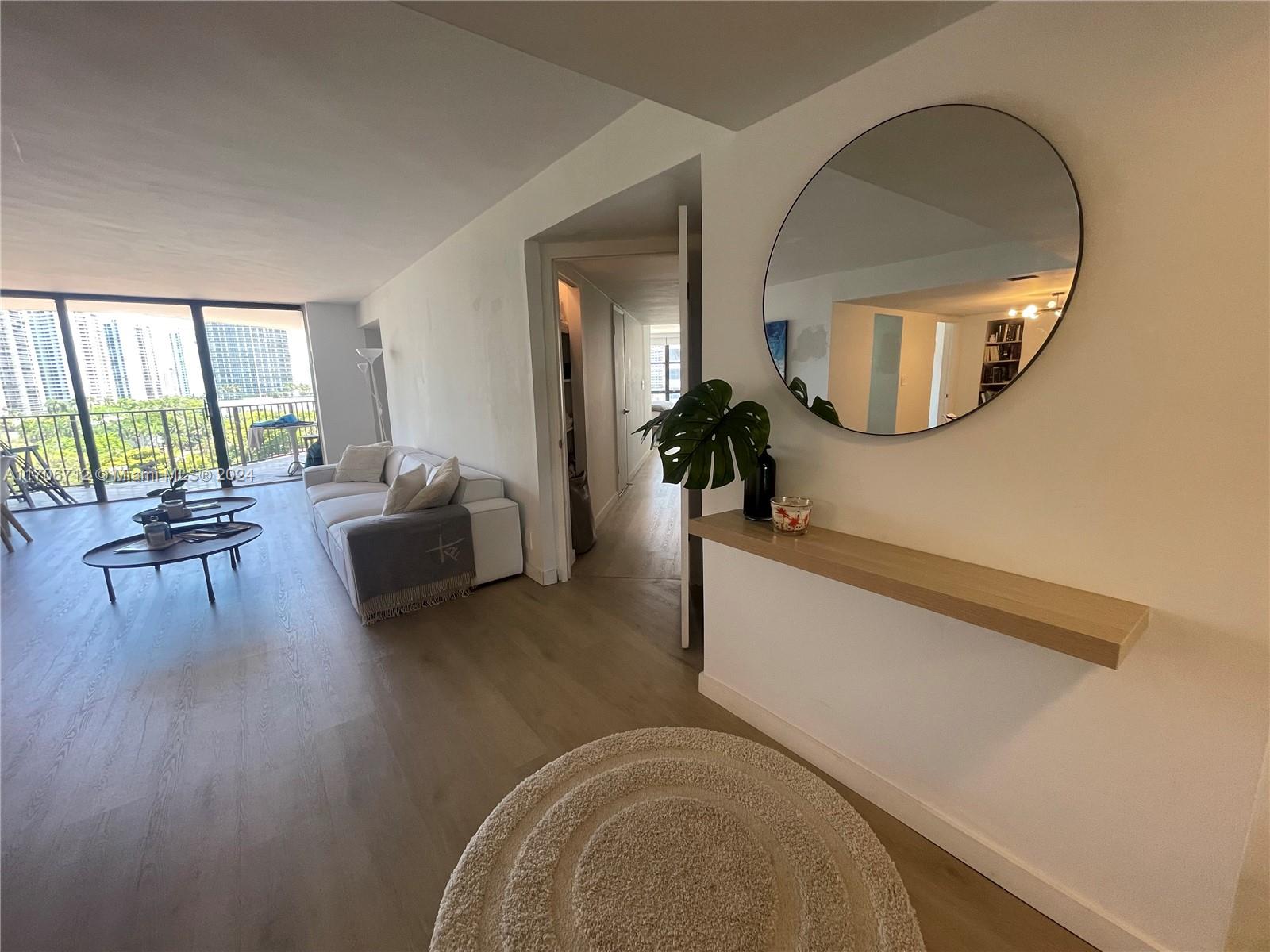 a living room with furniture and a large mirror next to a window