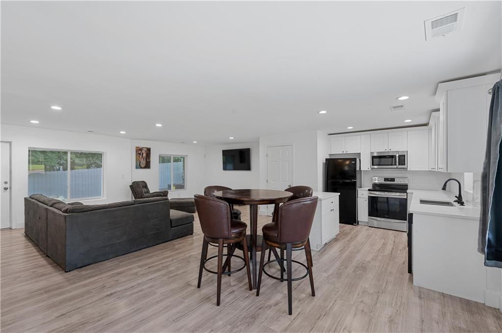 a living room with furniture a flat screen tv and kitchen view