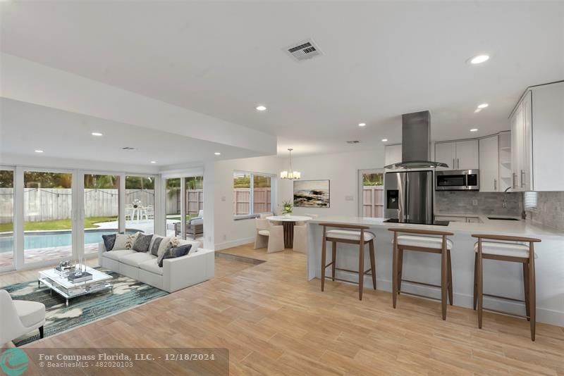 a living room with stainless steel appliances kitchen island granite countertop furniture and a wooden floor