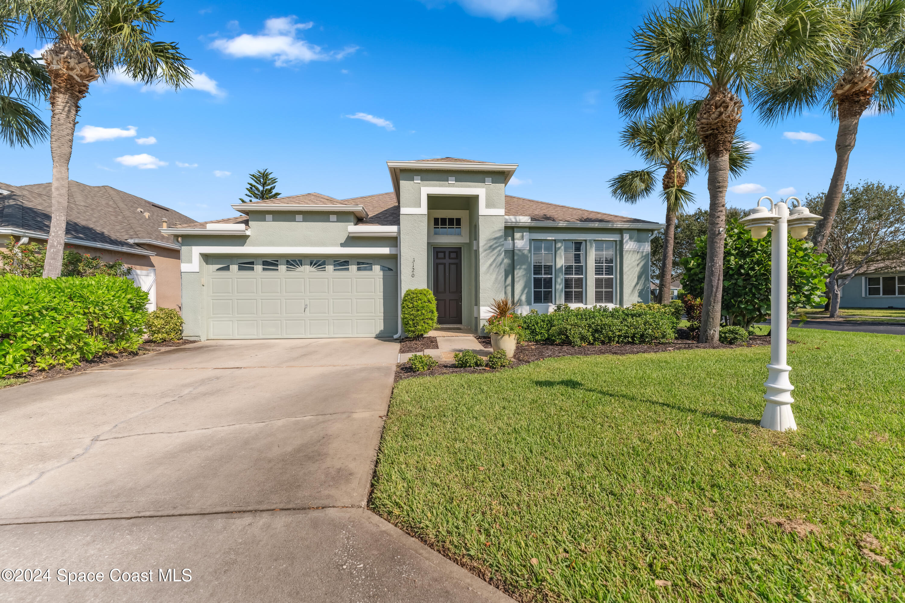 a front view of a house with a yard and palm trees