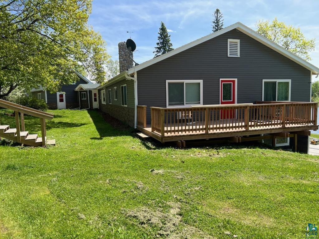 Rear view of property with a deck and a lawn